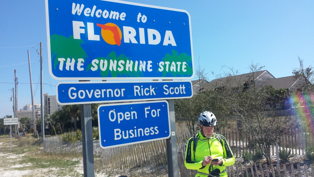 Tim checking his email on his phone under the Welcome to Florida sign